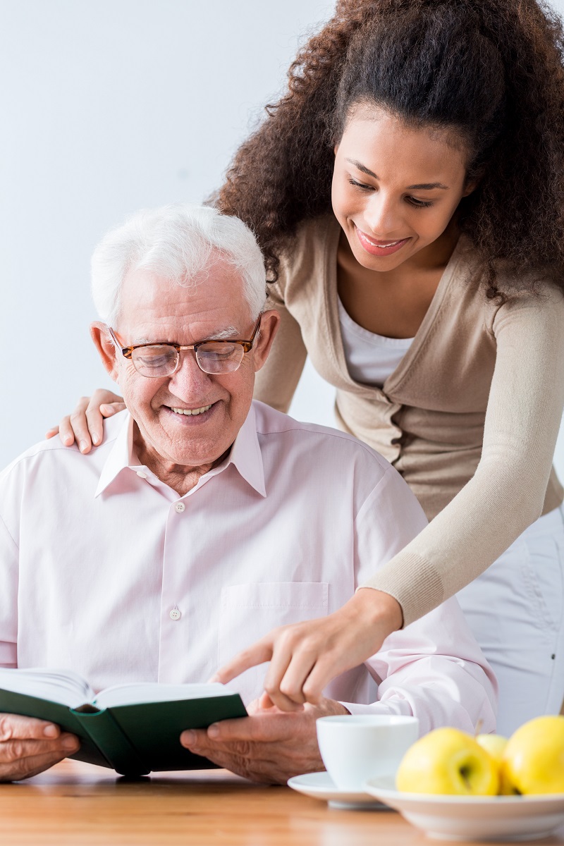 Caregiver reading with senior resident